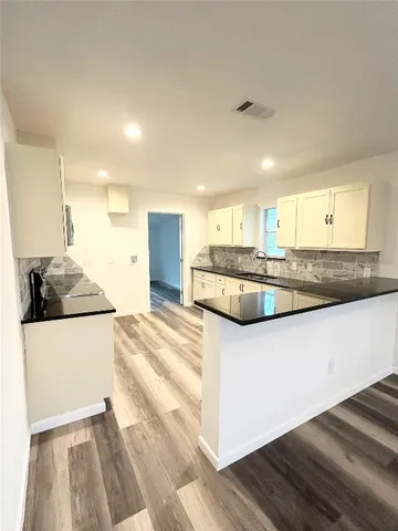 a large white kitchen with kitchen island granite countertop a sink and a stove top oven