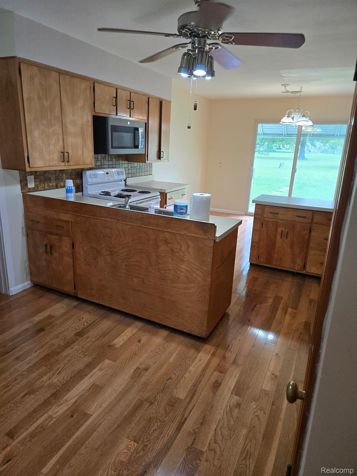 3176 East Fisher Road Bay City, MI 48706 - Photo 5 of 25 Kitchen featuring brown cabinetry, a peninsula, electric stove, dark wood-type flooring, and light countertops