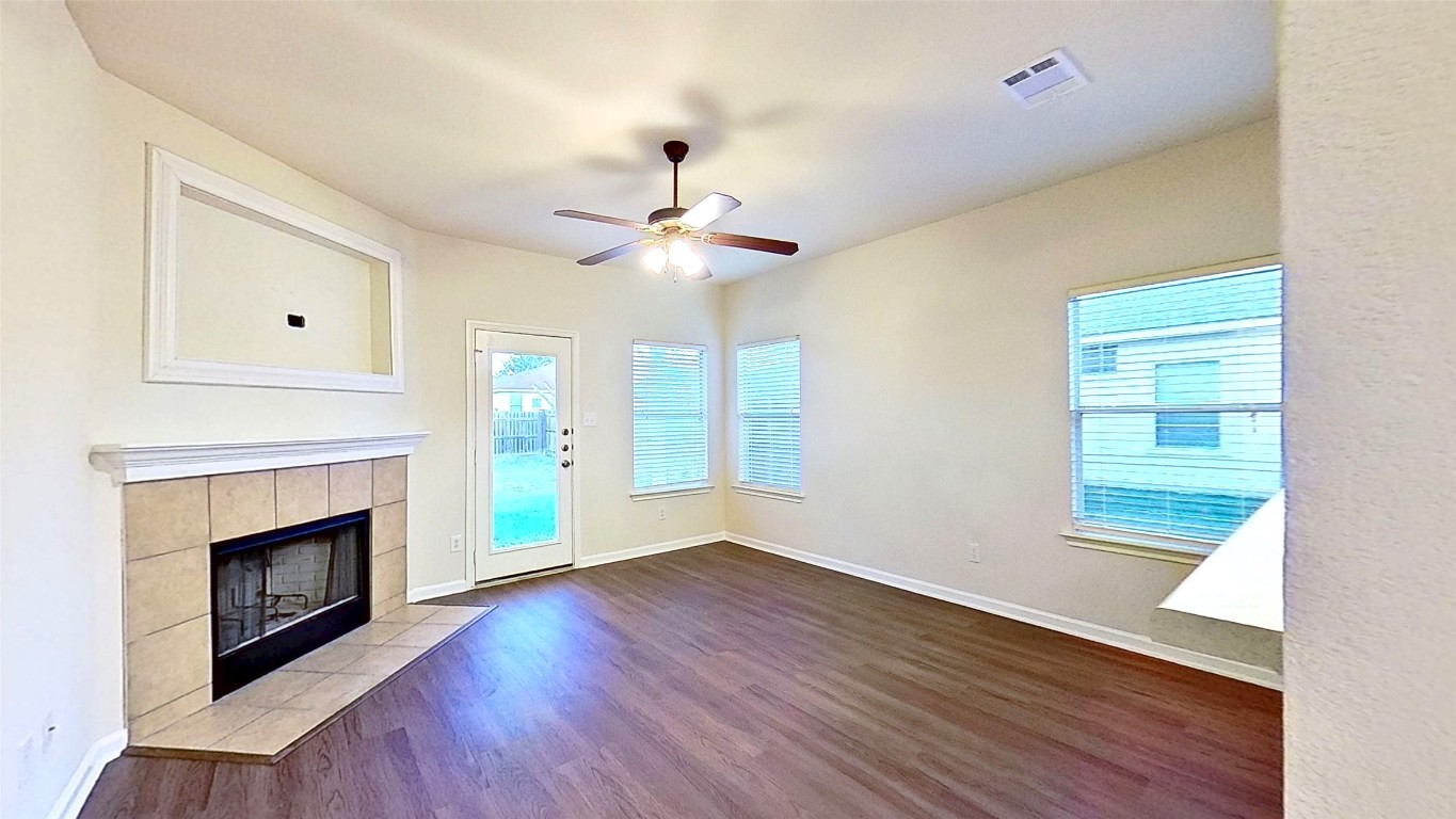 308 Rinehardt Street Hutto, TX 78634 - Photo 16 of 30 Unfurnished living room with dark wood-style flooring, a fireplace, and a ceiling fan