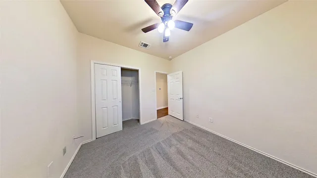 an empty room with windows and fan