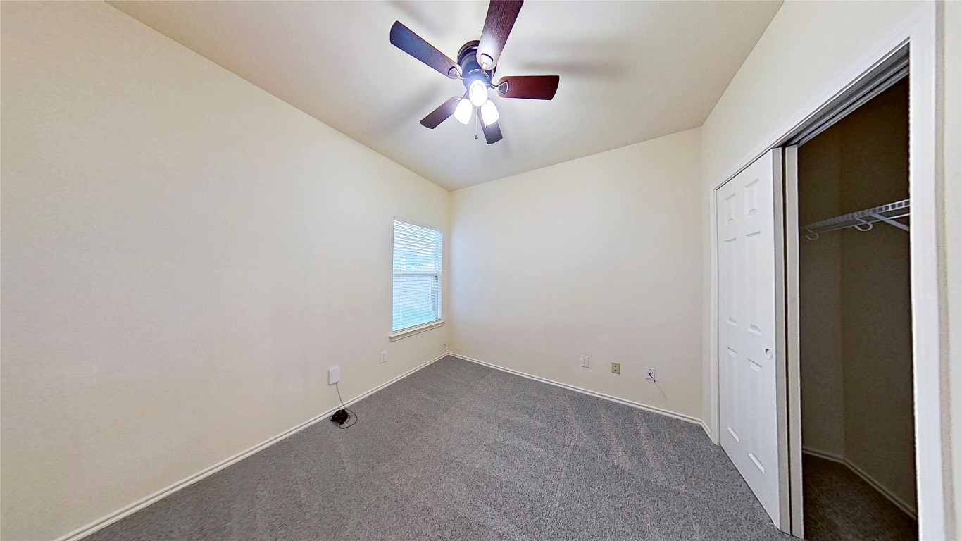 308 Rinehardt Street Hutto, TX 78634 - Photo 22 of 30 Unfurnished bedroom featuring a closet, dark carpet, and a ceiling fan