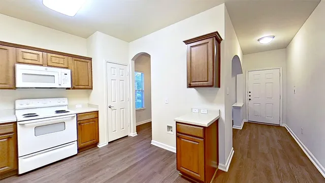 a kitchen with a refrigerator stove and wooden floor
