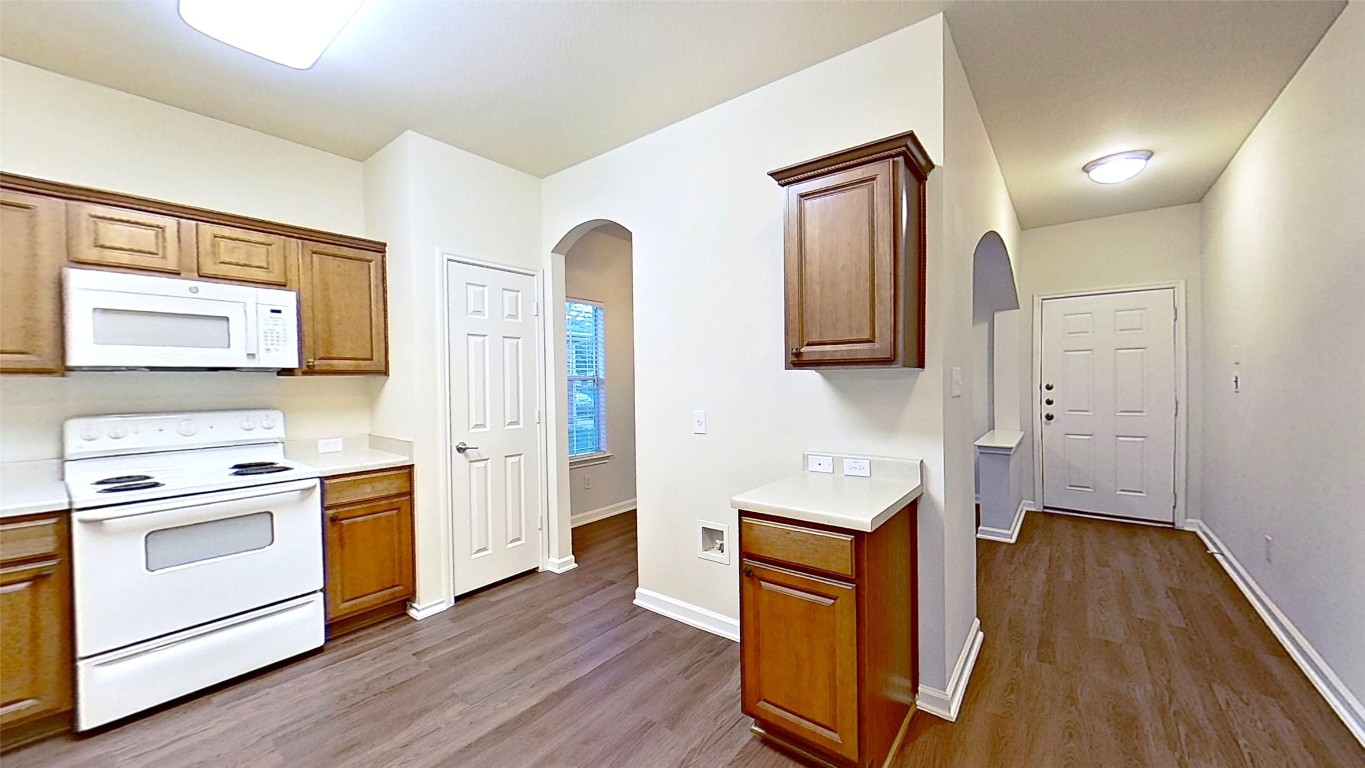 308 Rinehardt Street Hutto, TX 78634 - Photo 8 of 30 Kitchen with white appliances, light countertops, arched walkways, and light wood-style floors