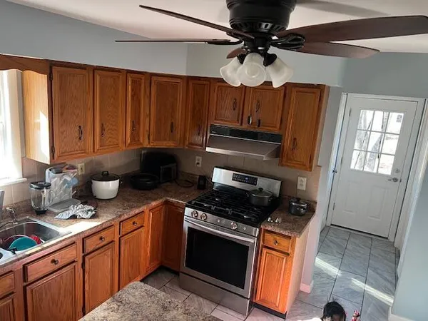 a kitchen with stainless steel appliances wooden cabinets a stove a sink and a microwave