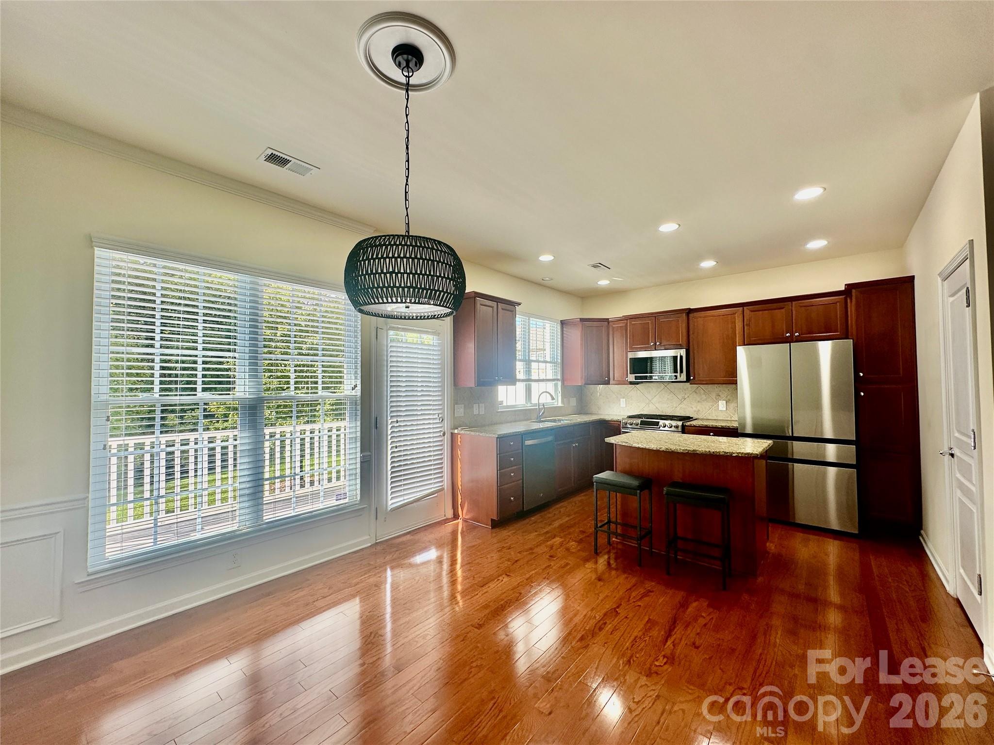1104 Drayton Court Fort Mill, SC 29708 - Photo 8 of 20 a room with stainless steel appliances kitchen island granite countertop a stove a refrigerator a sink a dining table and chairs with wooden floor