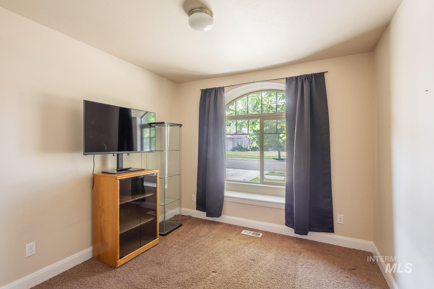 1186 East Observation Street Meridian, ID 83642 - Photo 25 of 33 Arched window with exterior streetscape, neutral wall paint, white trim, and brown carpeting