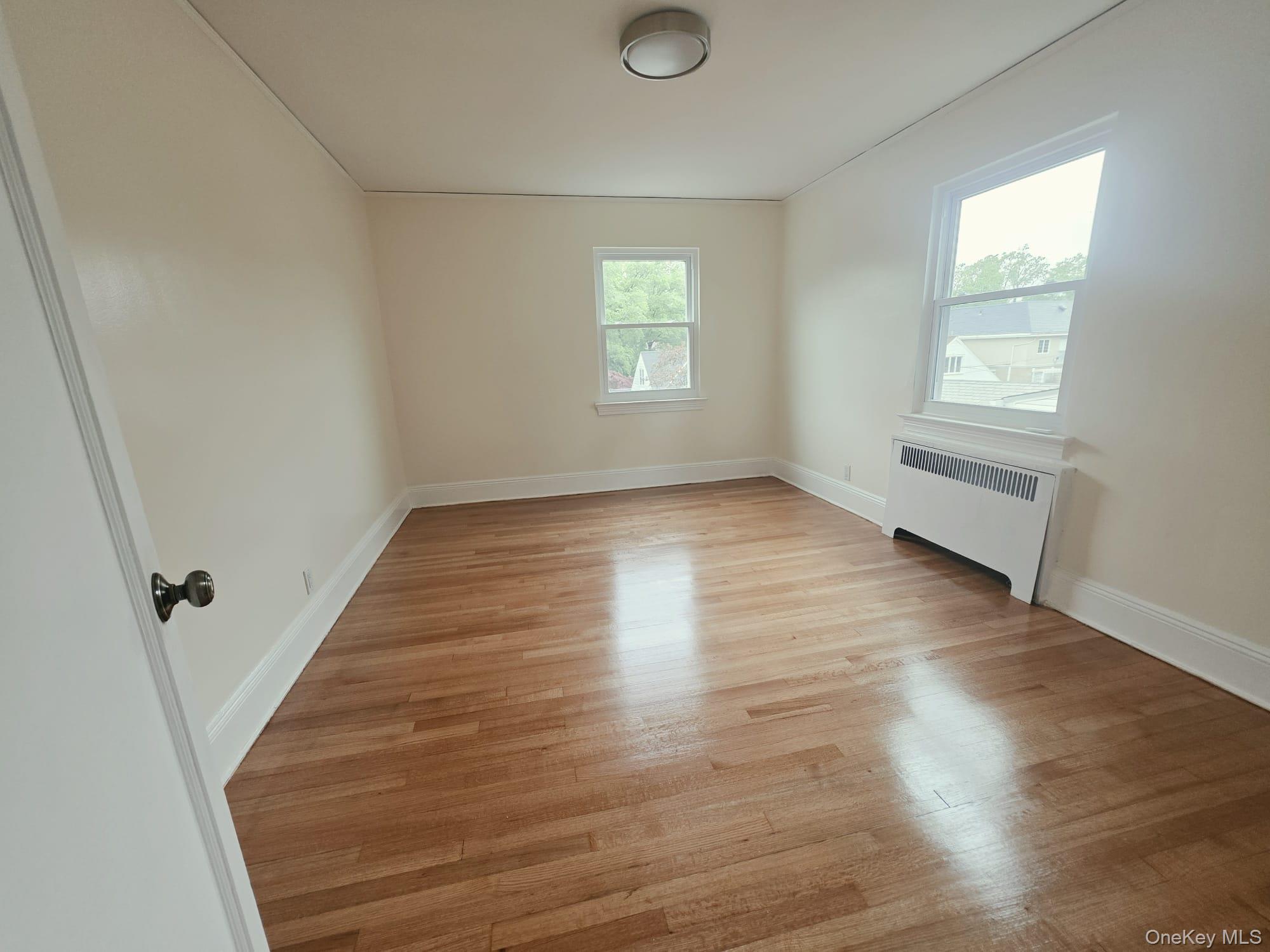180-15 Dalny Road Queens, NY 11432 - Photo 7 of 10 an empty room with wooden floor and windows