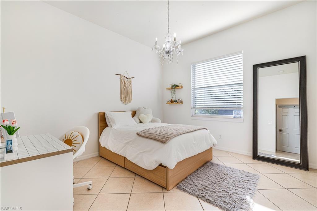 461 Everglades Boulevard North Naples, FL 34120 - Photo 11 of 16 Bedroom with light tile patterned floors and a chandelier