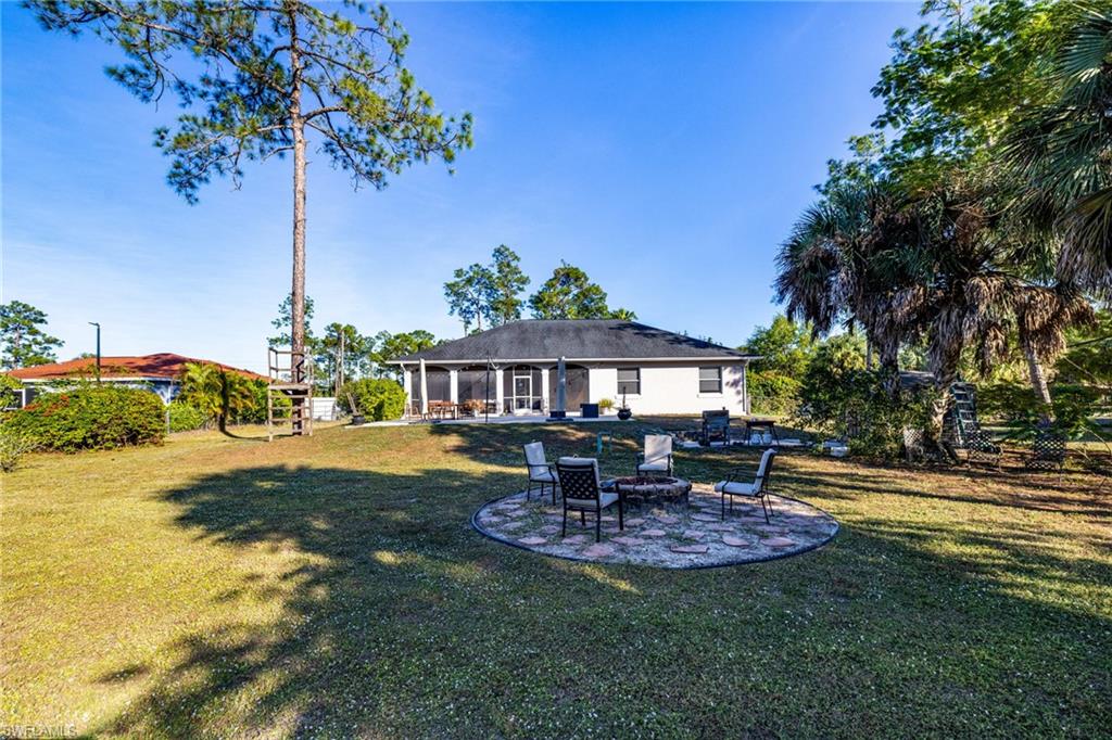 461 Everglades Boulevard North Naples, FL 34120 - Photo 16 of 16 Rear view of house featuring a patio, a fire pit, a sunroom, and a yard