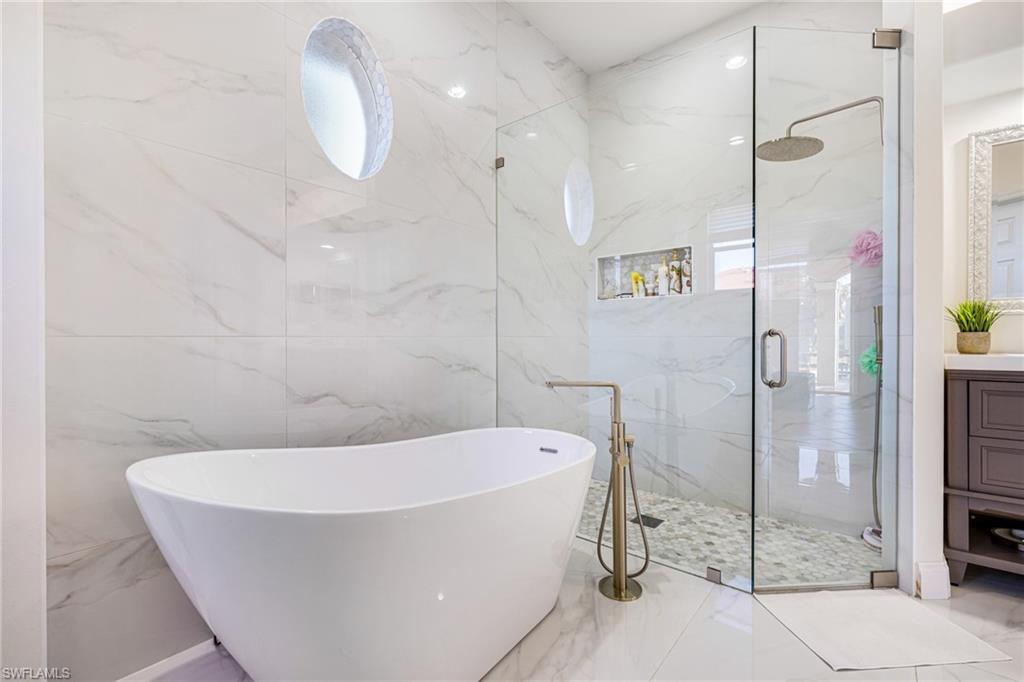 461 Everglades Boulevard North Naples, FL 34120 - Photo 10 of 16 Bathroom with a marble finish shower, vanity, and a freestanding tub