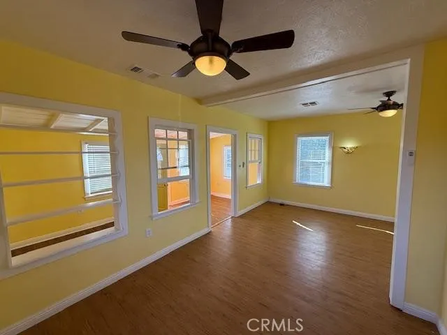a view of an empty room with window and wooden floor