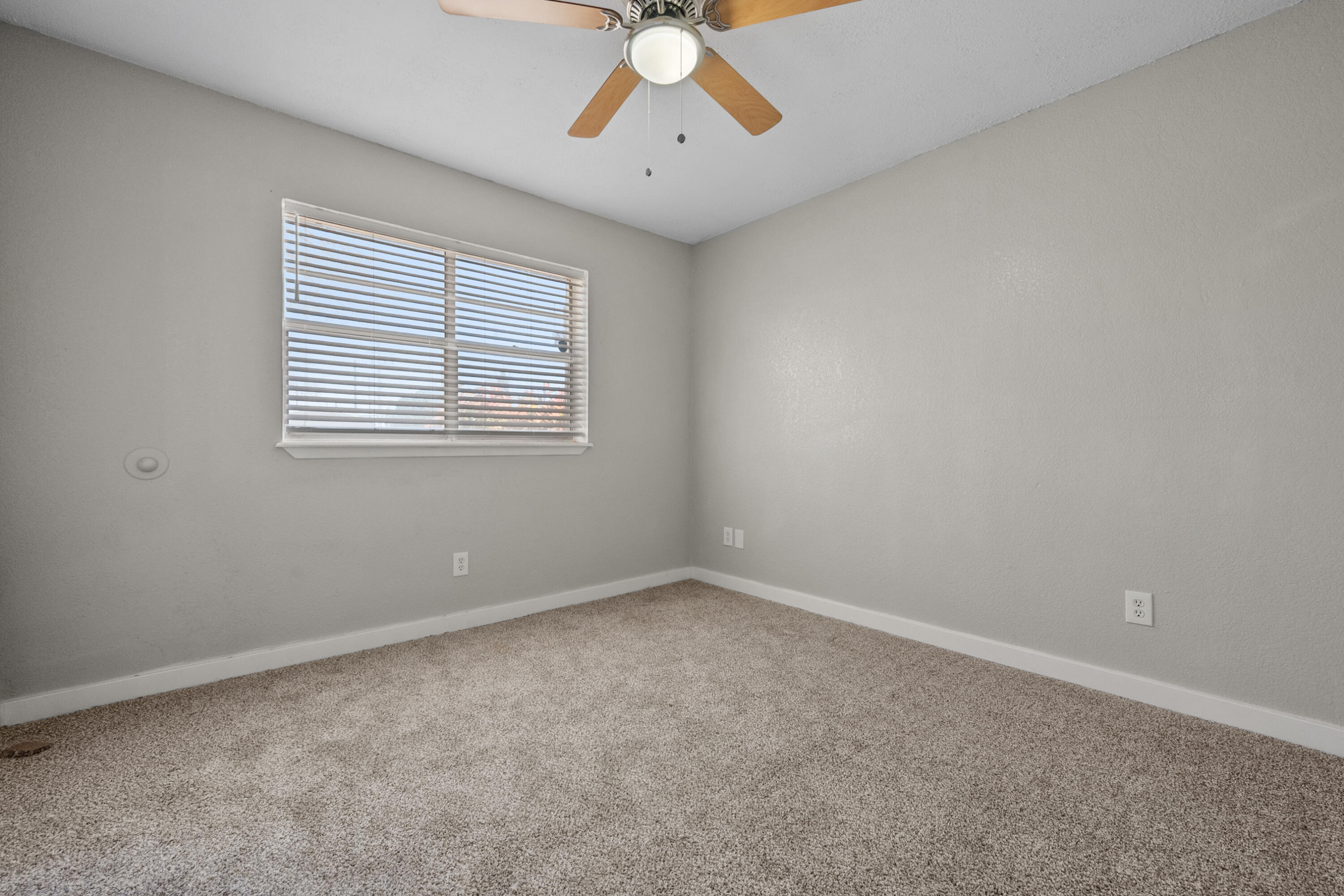 8110 Uvalde Avenue Lubbock, TX 79423 - Photo 5 of 11 an empty room with a chandelier fan and windows