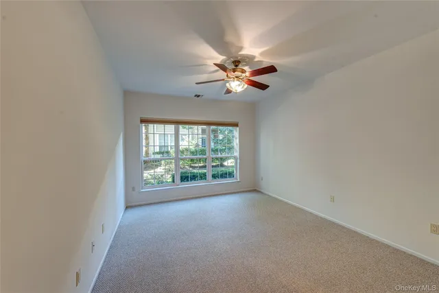 an empty room with windows and fan