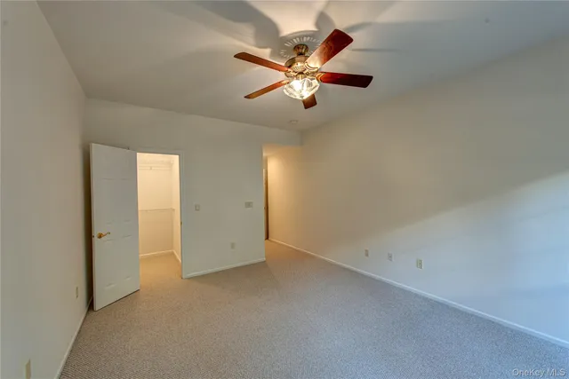 an empty room with closet and a chandelier fan