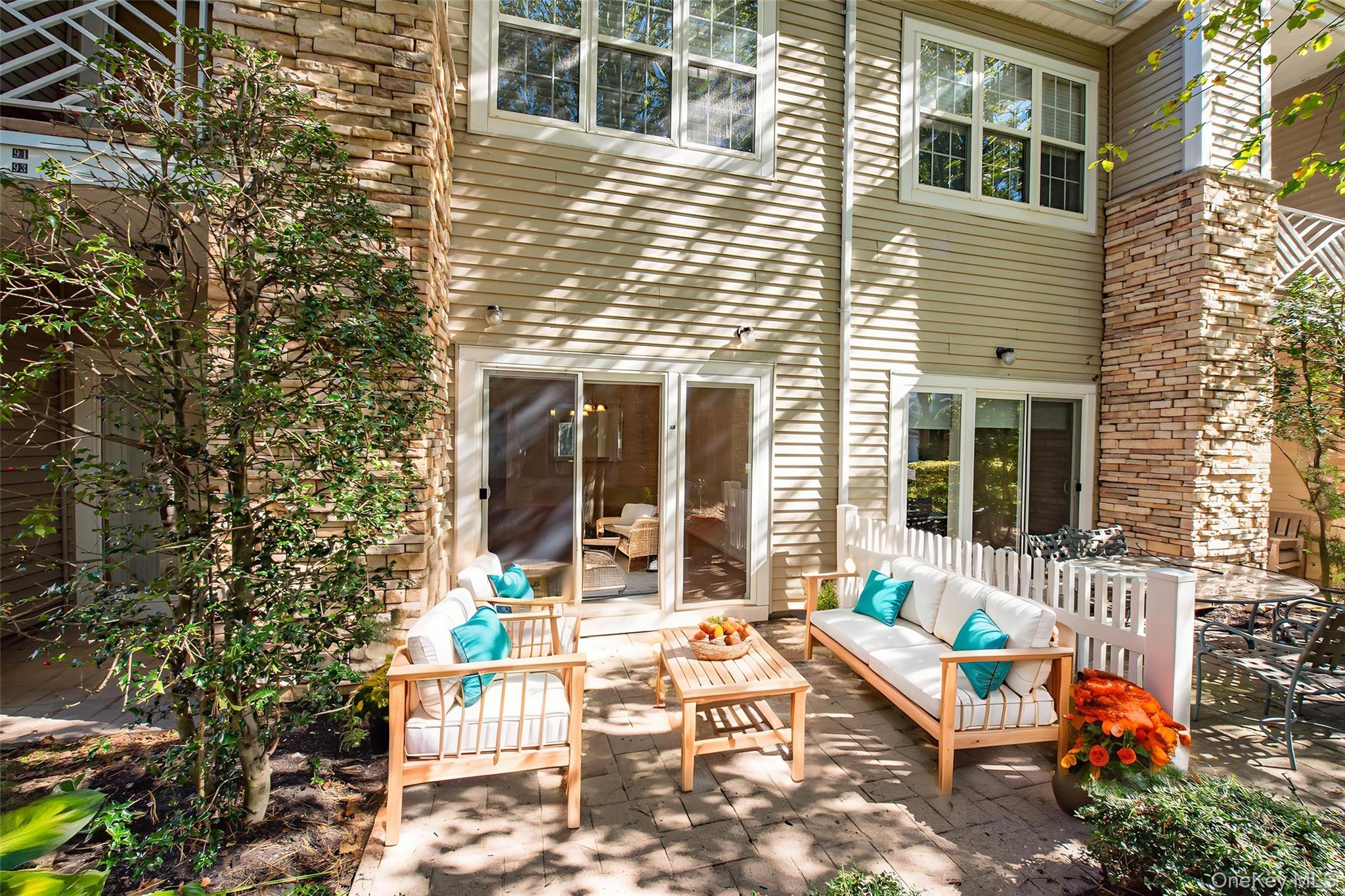 93 Carriage Lane, Unit AVON LOWER Plainview, NY 11803 - Photo 27 of 36 a view of a patio with a table and chairs and potted plants