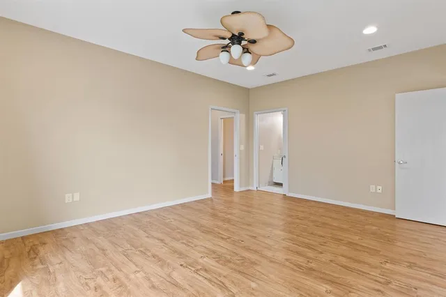 a view of an empty room and chandelier fan