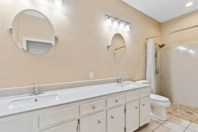 a bathroom with a double vanity sink mirror and toilet