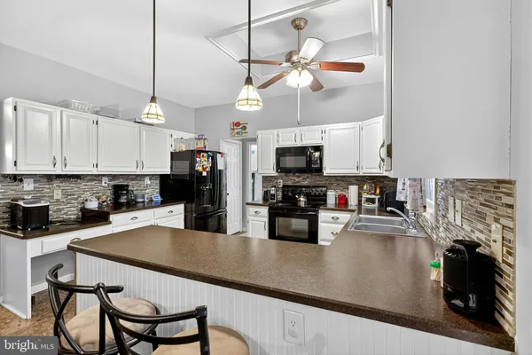 a kitchen with stainless steel appliances kitchen island granite countertop a refrigerator a stove a sink a stove and white cabinets with wooden floor