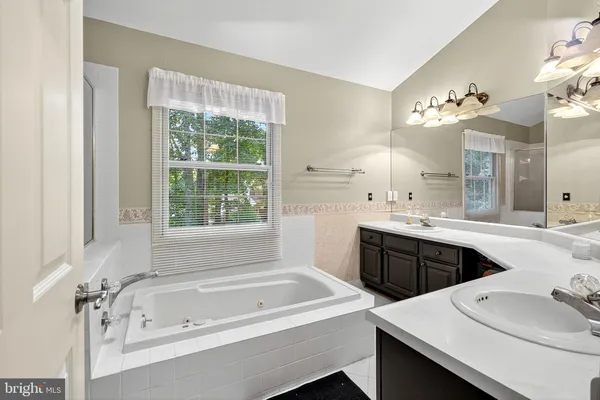a bathroom with a tub a sink double vanity and a window