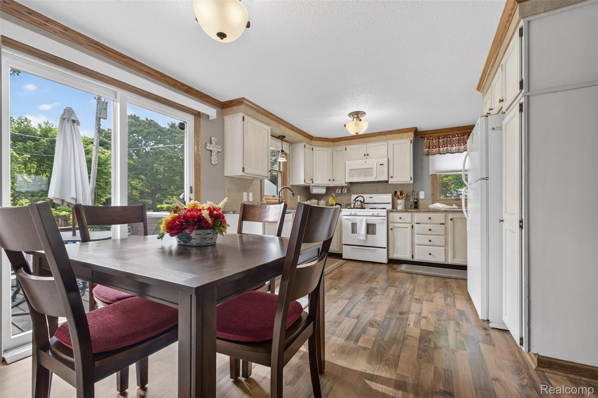 5977 Anglers Road Ortonville, MI 48462 - Photo 9 of 63 Kitchen and dining area featuring wood-finish flooring, white cabinetry, and white appliances