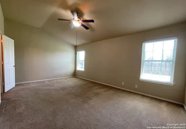 an empty room with windows and fan