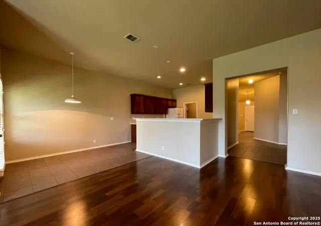 a view of a kitchen with a fridge and wooden floor