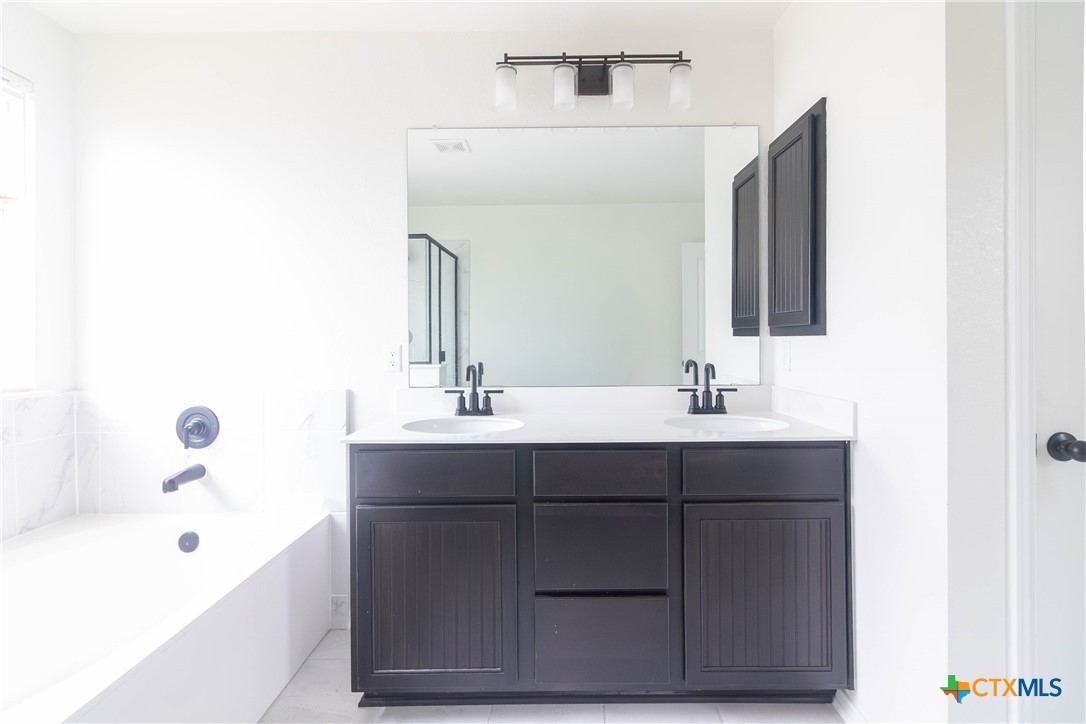 1131 Aronia Lane Georgetown, TX 78626 - Photo 30 of 36 a bathroom with a sink double vanity granite tub shower and a mirror