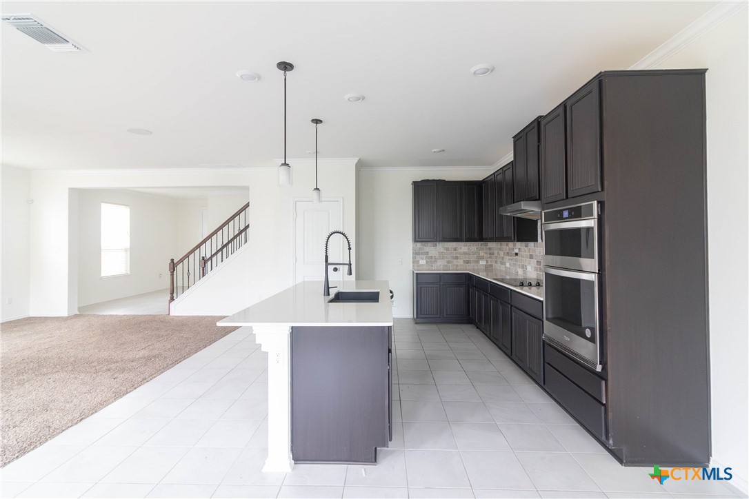 1131 Aronia Lane Georgetown, TX 78626 - Photo 7 of 36 a kitchen with stainless steel appliances kitchen island granite countertop a refrigerator a stove and a sink with wooden floor