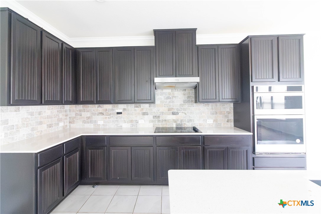 1131 Aronia Lane Georgetown, TX 78626 - Photo 9 of 36 a kitchen with stainless steel appliances a sink a stove and wooden cabinets