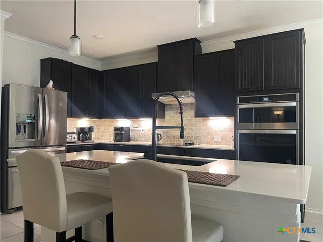 a kitchen with stainless steel appliances granite countertop a refrigerator a stove and a sink with wooden floor