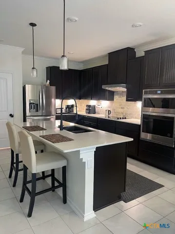a kitchen with stainless steel appliances a sink a stove a refrigerator and cabinets
