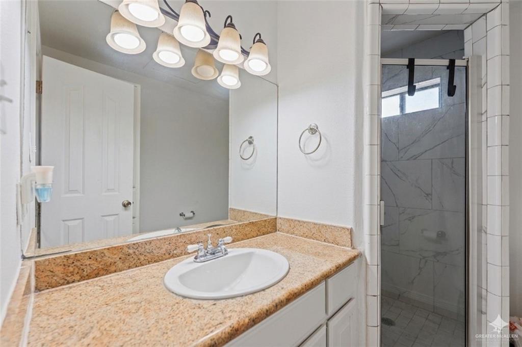24175 Engleman Road Edcouch, TX 78538 - Photo 20 of 22 a bathroom with a granite countertop sink a mirror and a shower