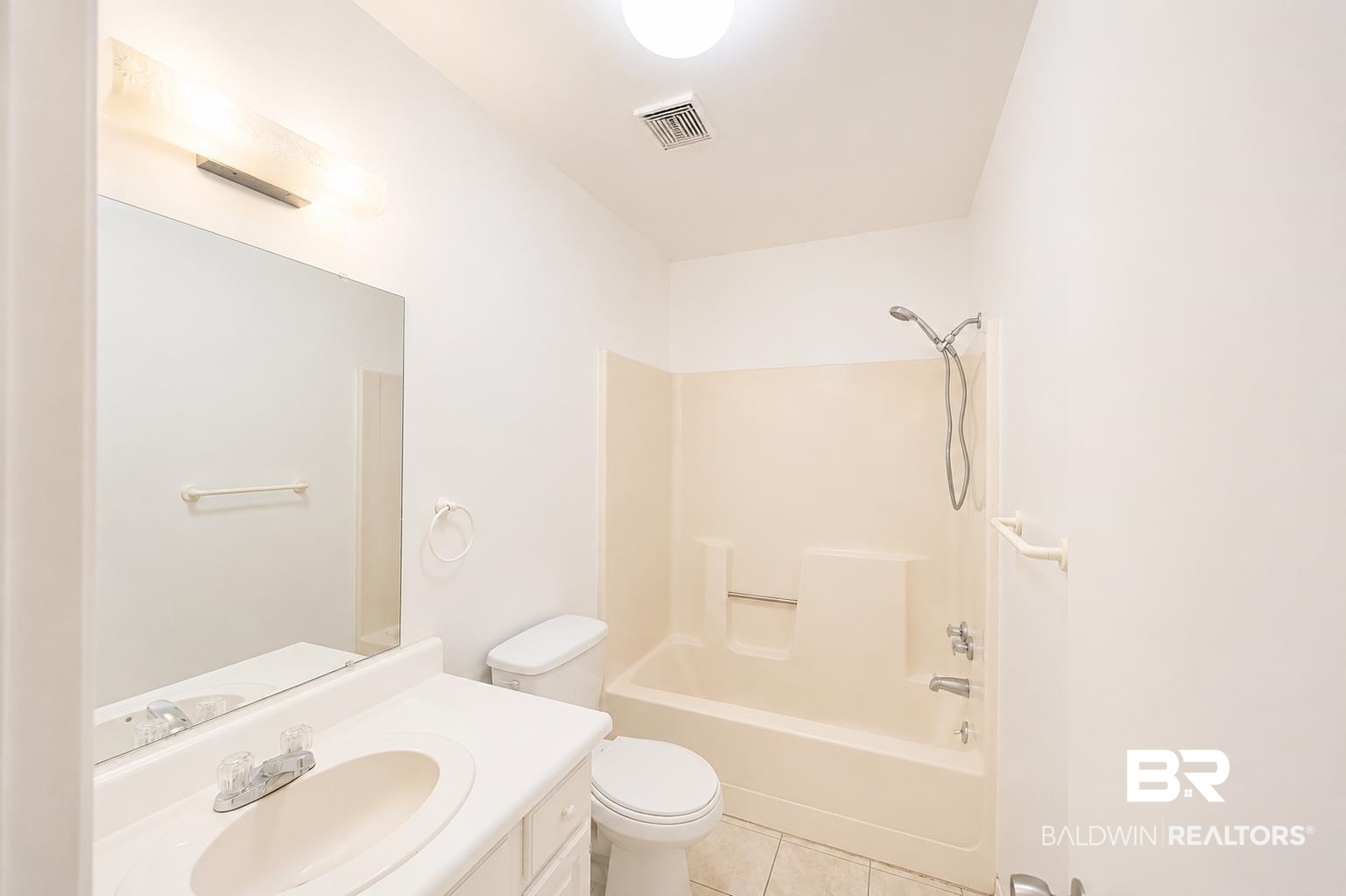 614 East Gate Circle Foley, AL 36535 - Photo 19 of 31 Bathroom featuring a vanity with an integrated sink, a rectangular mirror, a light fixture, a toilet, and a bathtub with an integrated shower head