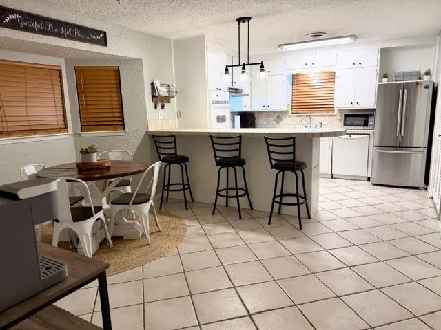 a kitchen with stainless steel appliances kitchen island granite countertop a table chairs and a refrigerator