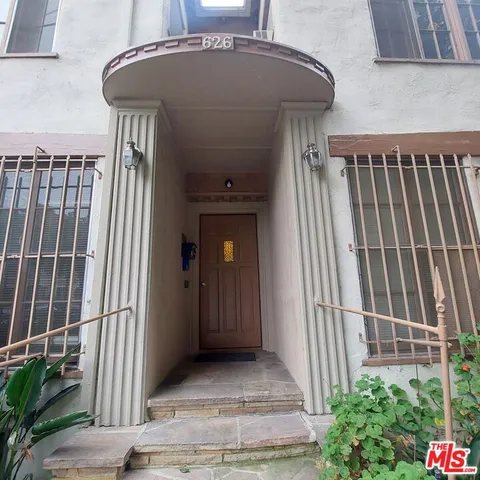 a view of a house with a small yard and potted plants