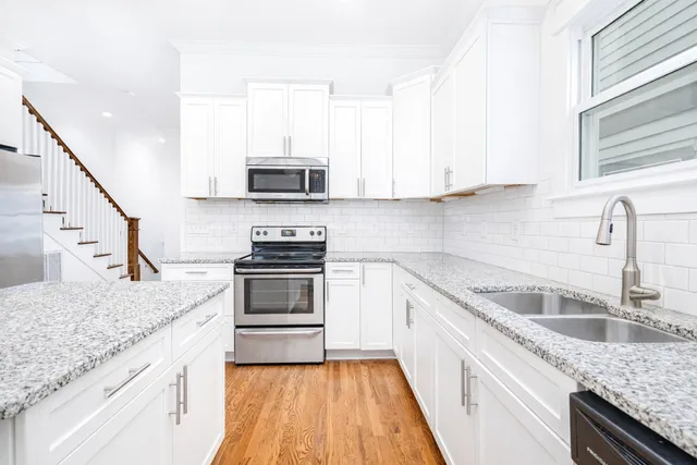 a kitchen with granite countertop a sink stove and cabinets