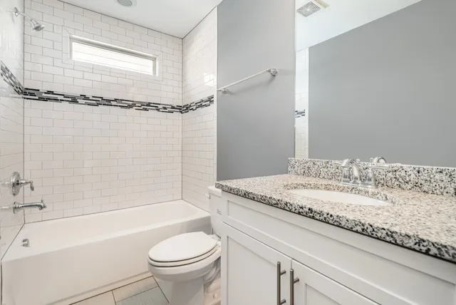 a bathroom with a granite countertop sink a toilet and shower