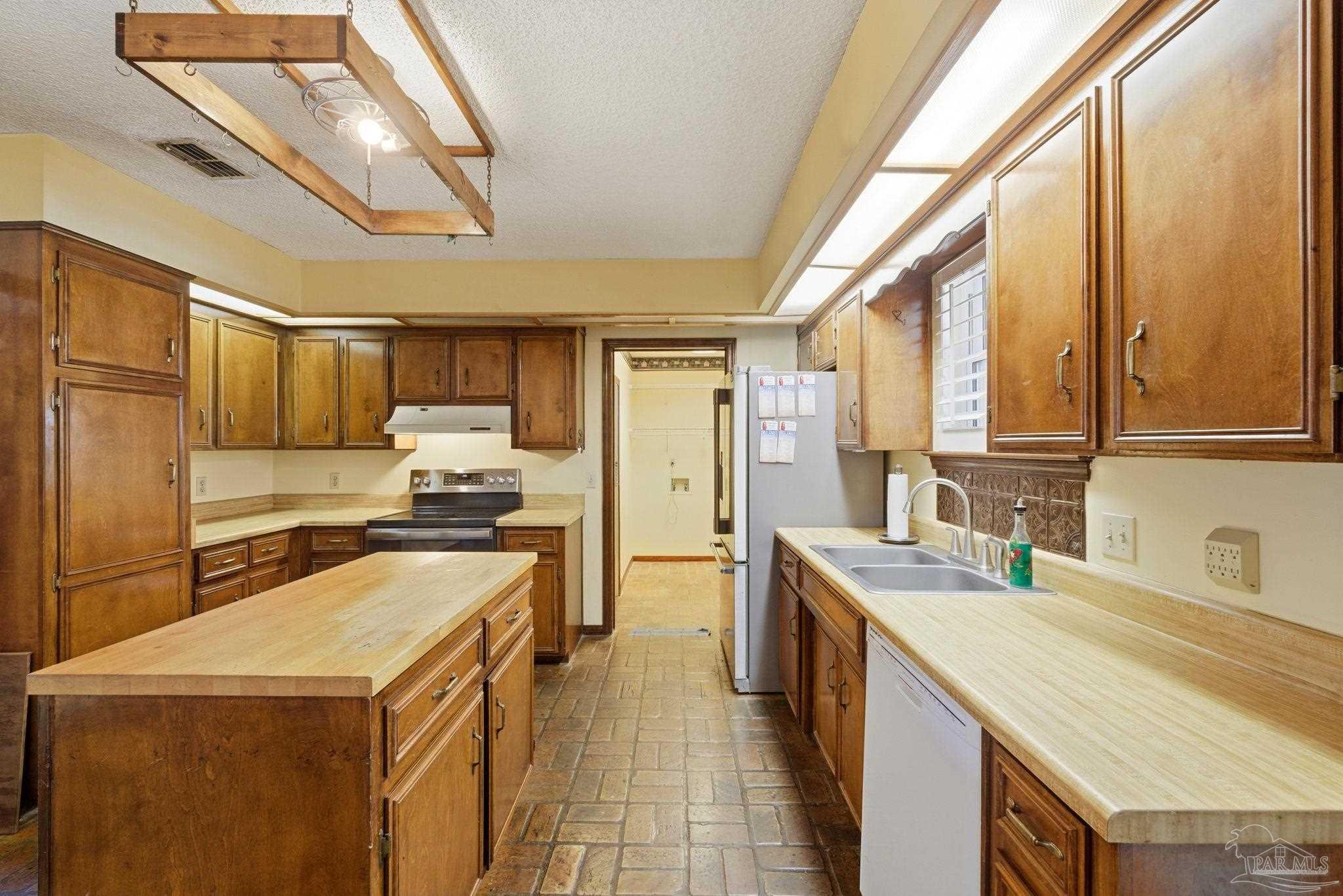 934 Springmier Place Pensacola, FL 32514 - Photo 10 of 49 a kitchen with a stove a sink a refrigerator and cabinets