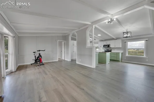 a view of a livingroom with wooden floor and kitchen view