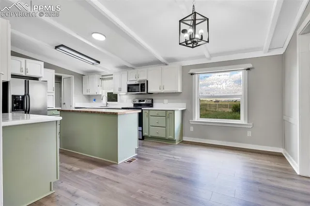 a kitchen with stainless steel appliances granite countertop a sink a stove a refrigerator cabinets and a window