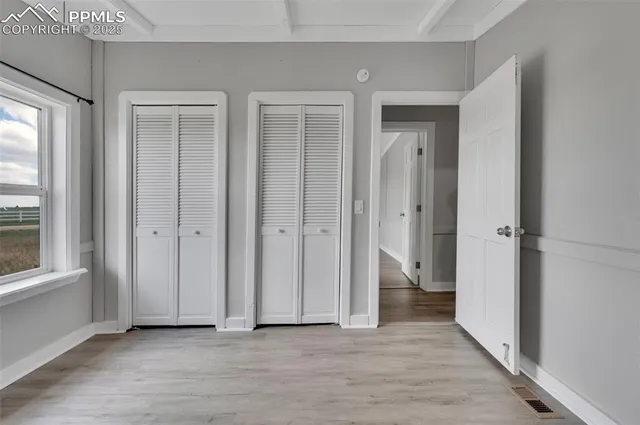 a view of an empty room with closet and a window