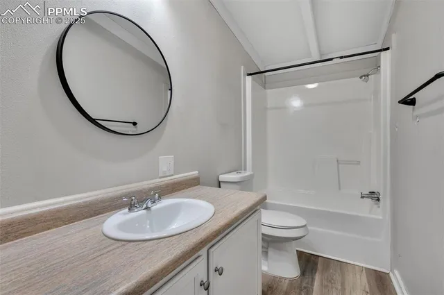 a bathroom with a granite countertop sink toilet mirror vanity and shower