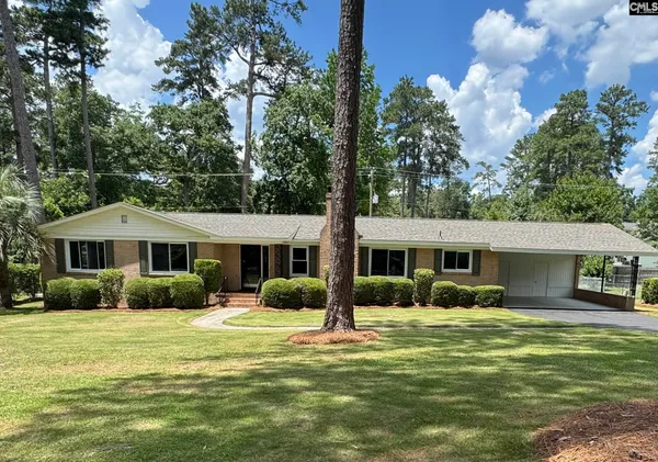 a front view of a house with garden and trees