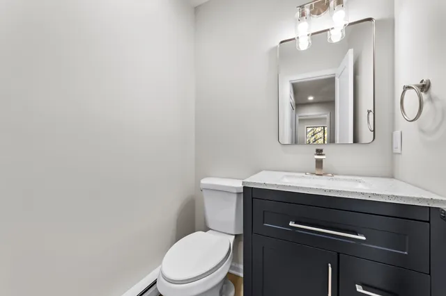 a bathroom with a granite countertop toilet sink and mirror
