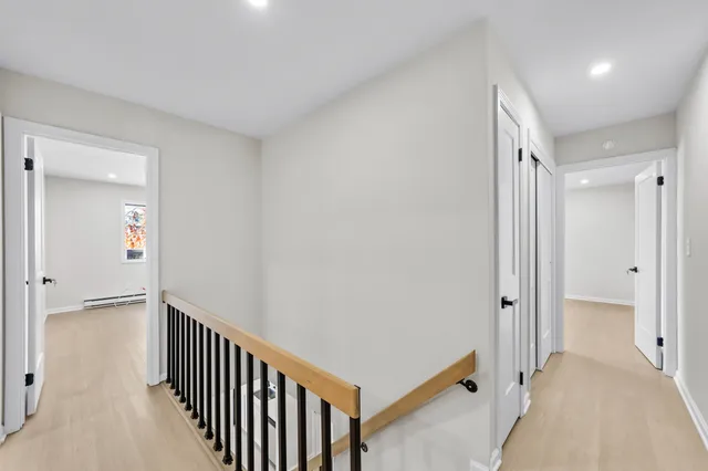a view of a hallway with wooden floor and a bathroom