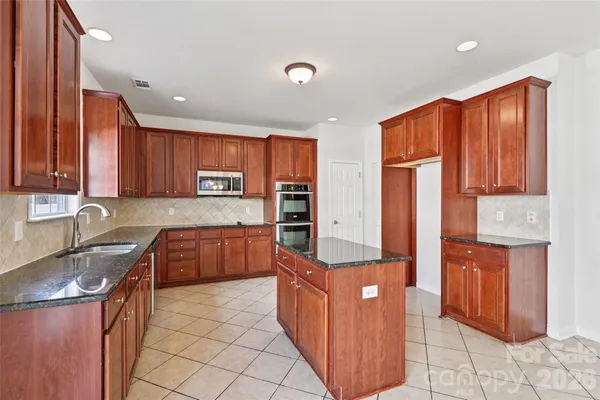 a kitchen with stainless steel appliances granite countertop wooden cabinets a washer and dryer