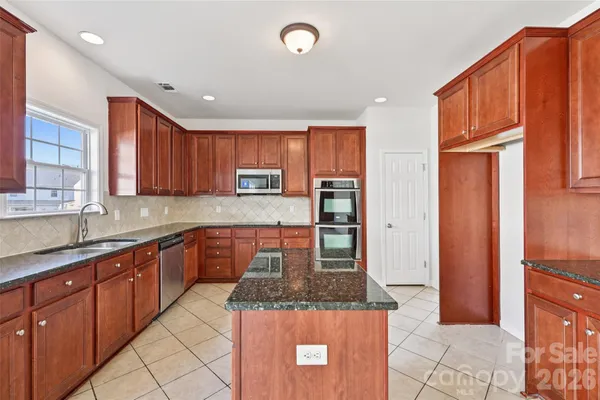 a kitchen with stainless steel appliances granite countertop wooden cabinets a sink and a stove