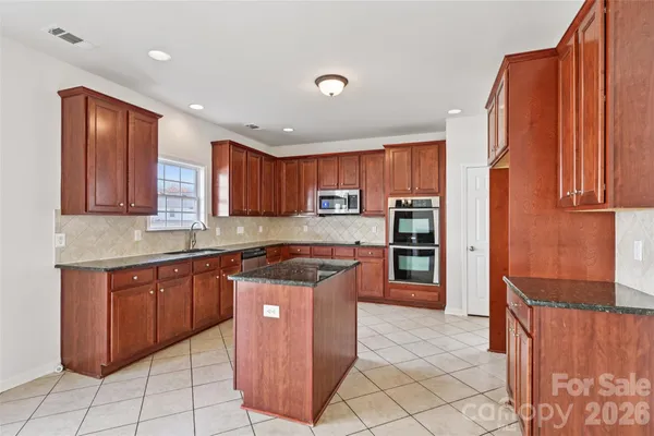 a kitchen with stainless steel appliances granite countertop a stove top oven a sink and dishwasher