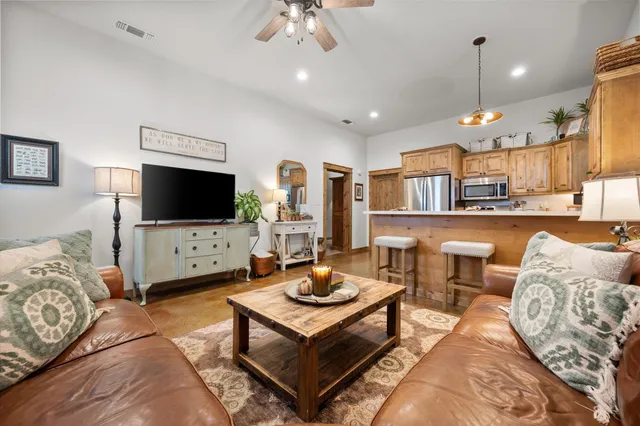 a kitchen with stainless steel appliances granite countertop a refrigerator a sink dishwasher a dining table and chairs with wooden floor