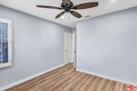 a view of a room with a ceiling fan and wooden floor